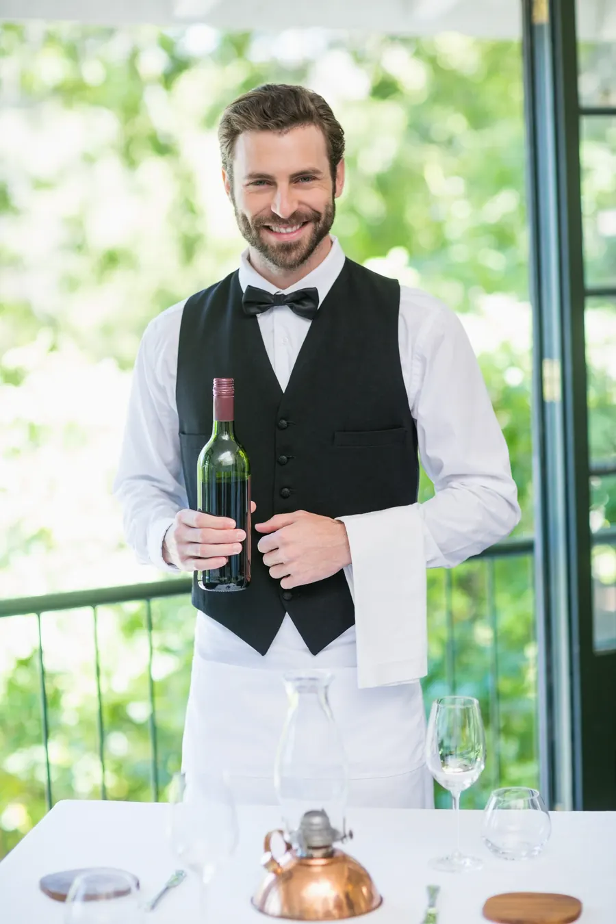 Maître d'hôtel en tablier noir qui sert le vin lors d'un dîner de mariage