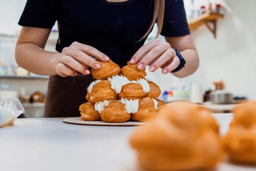 Pâtissière qui monte une pièce montée en choux, caramel