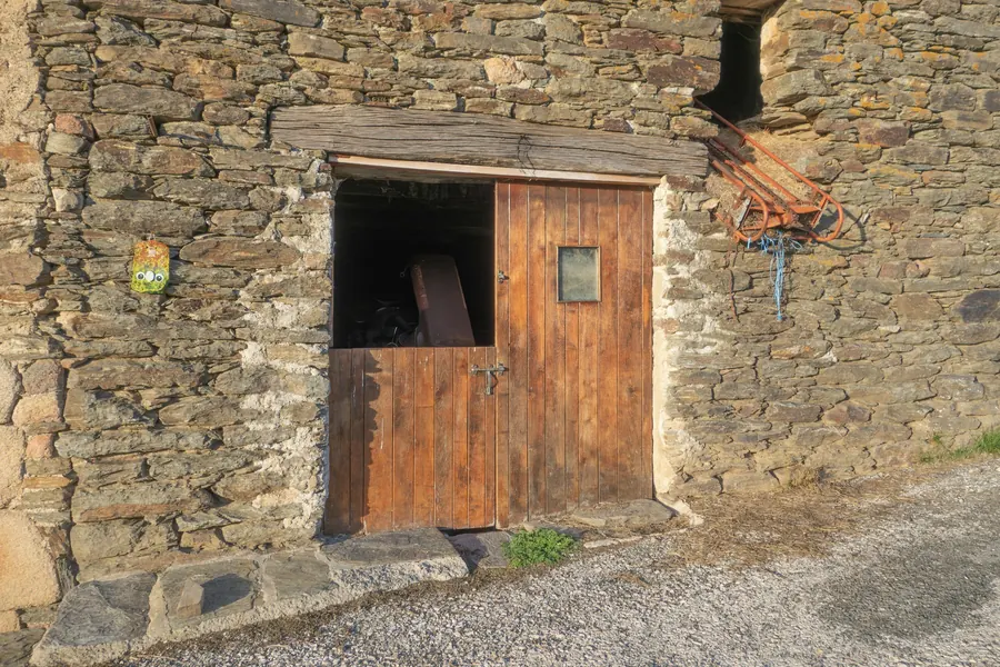 Porte en bois ouverte sur un bâtiment en pierre, sans légumes visibles