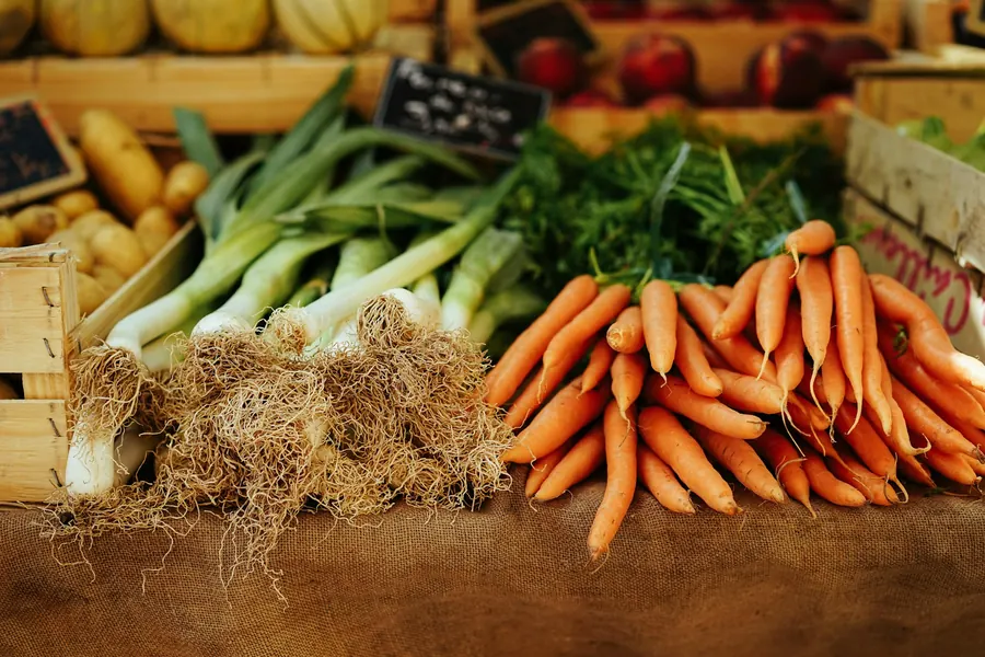 Cagette en bois pleine de légumes d'automne : poireaux, courge, carottes, chou, terre encore visible