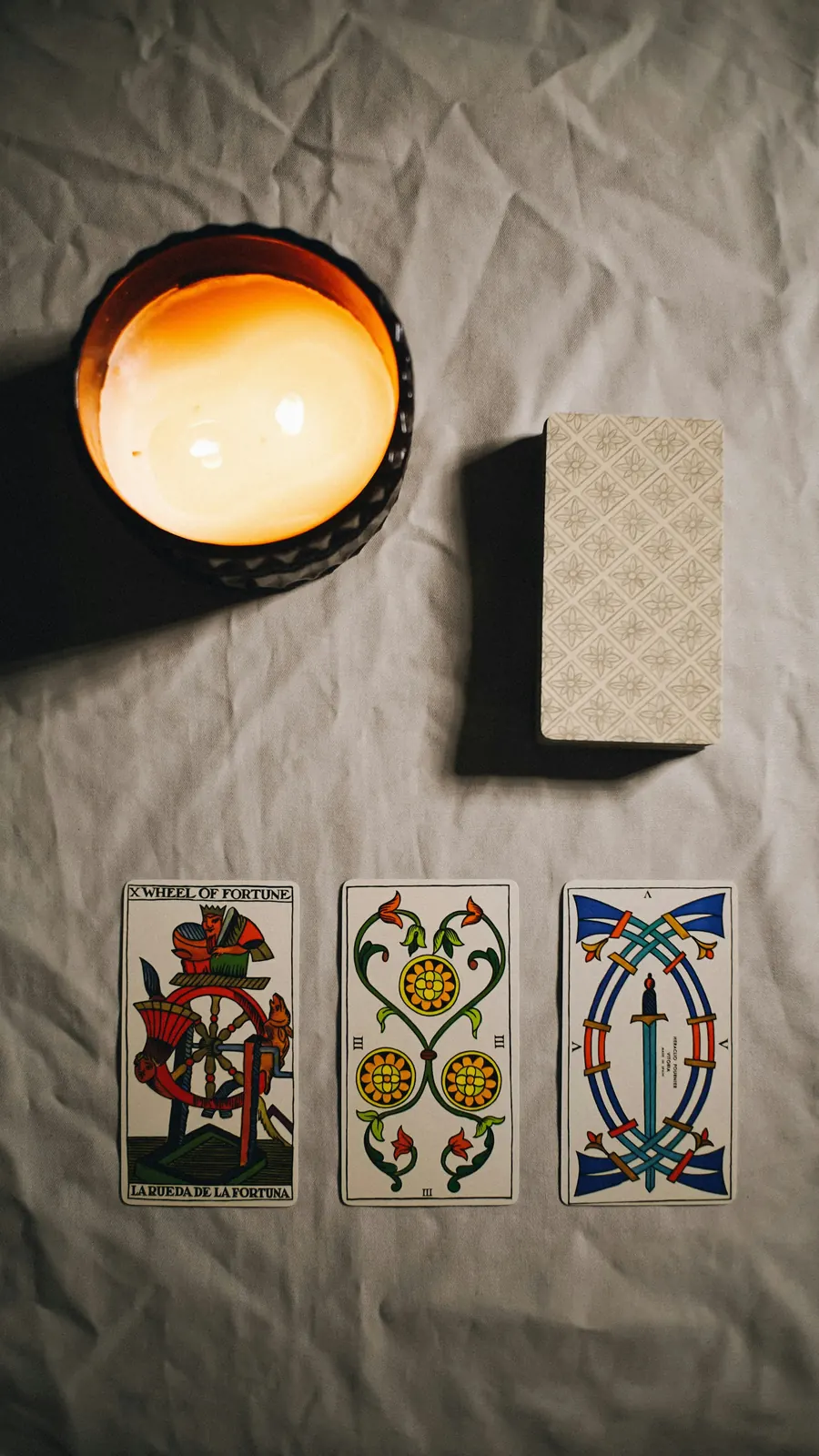 Quelques cartes de tarot et une bougie sur un tissu