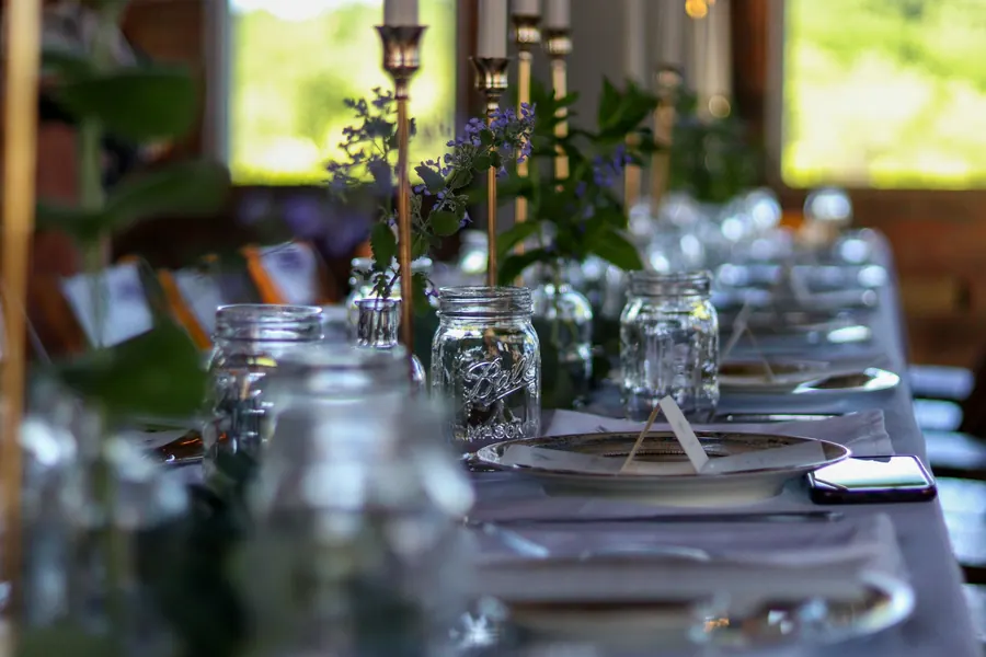 Longue table de mariage dressée en extérieur à la tombée du jour, sans grange ni guirlandes visibles