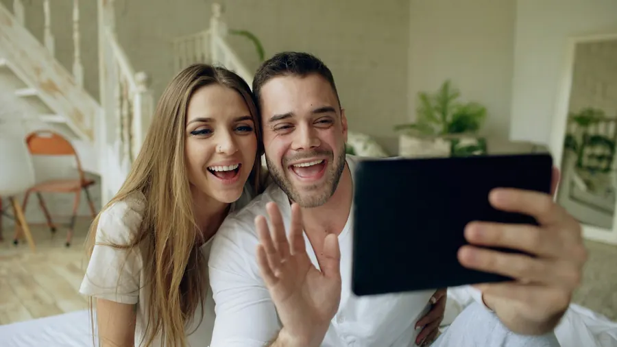 Jeune couple souriant lors d'un appel vidéo sur tablette