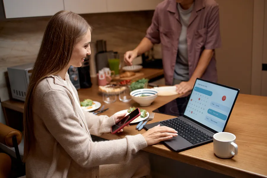Femme posant une question à un assistant sur son ordinateur, dans sa cuisine