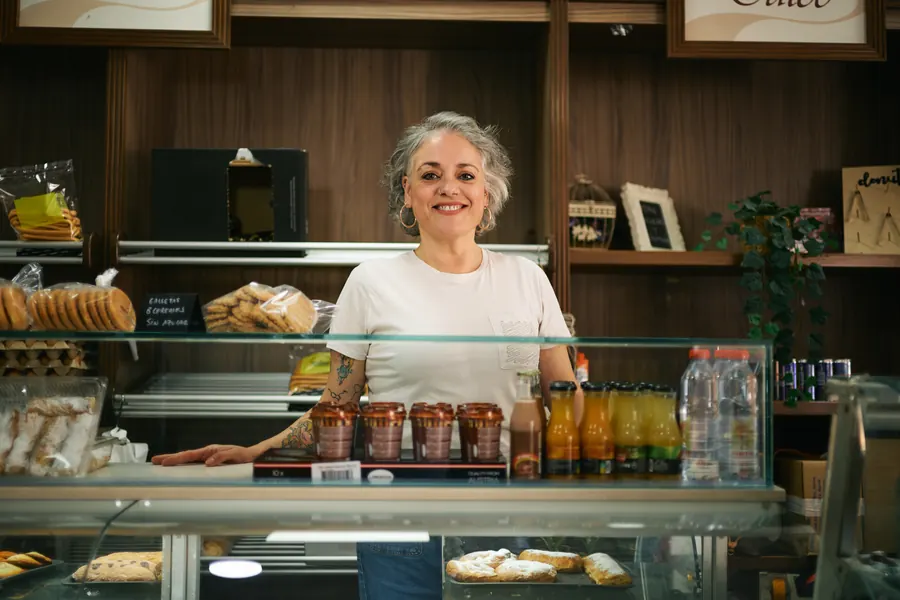 Commerçante souriante derrière le comptoir de son épicerie fine