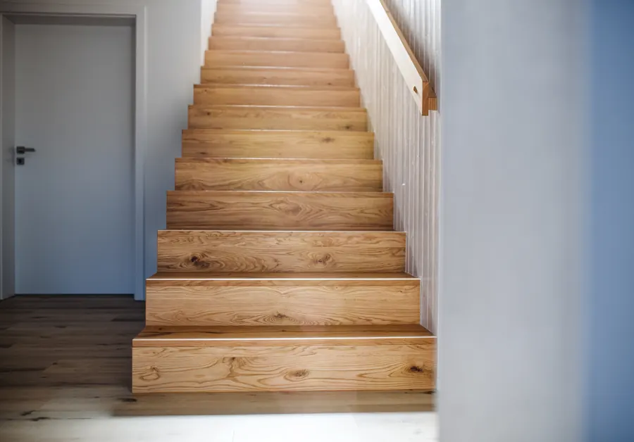 Un escalier en bois contre un mur blanc