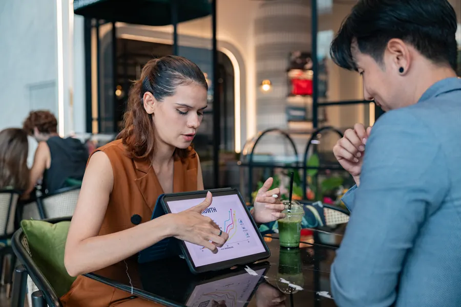 Présentation d’une maquette sur tablette à un client, dans un café