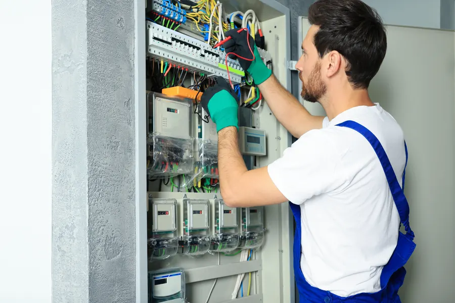 Un électricien contrôle un tableau électrique avec un multimètre