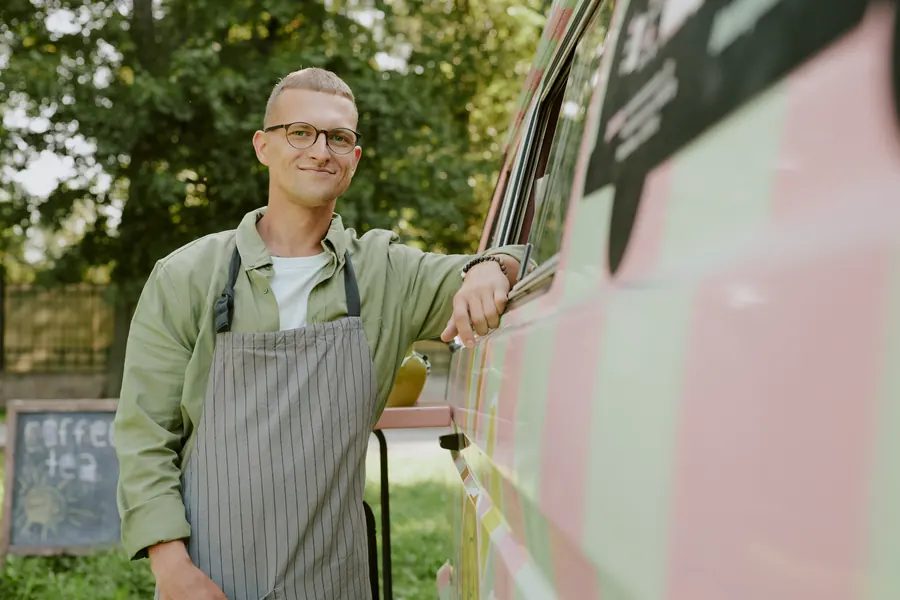 Le gérant souriant devant son food truck coloré