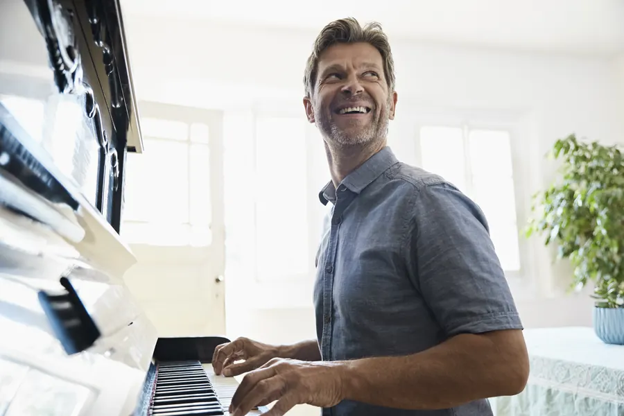 Un professeur souriant joue du piano à queue