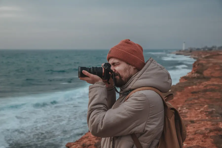 Un photographe au bord d'une falaise face à la mer